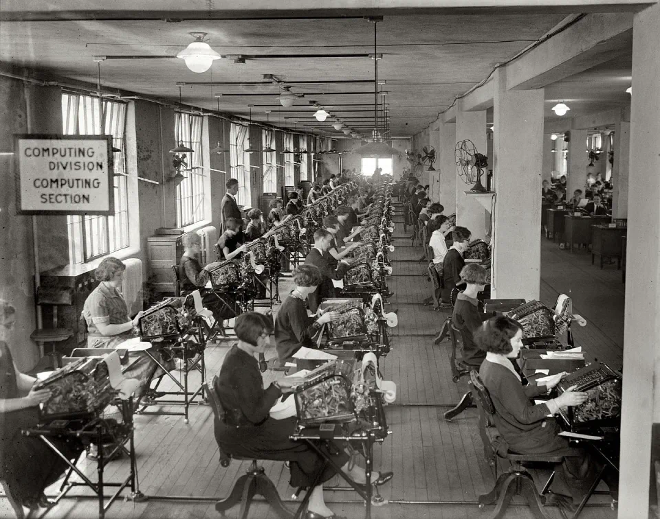 Rows of women seated at and operating now-antiquated mechanical calculators.